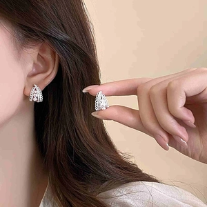 Detailed view of silver lace earrings with three vertical pearls on a model ear