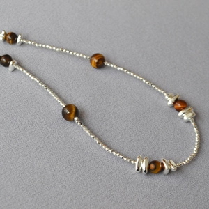 Macro shot of tiger eye beads and silver spacers on a layered beaded necklace