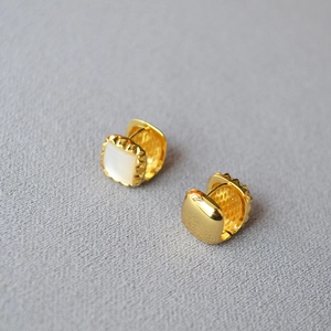 Macro detail of gold plated square earring with white mother of pearl and rivet edges