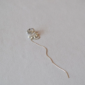 Detail of silver ear cuff with white pearls and a long delicate fringe chain tassel