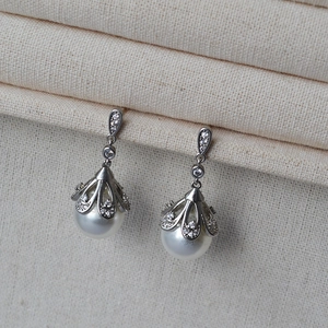 Close-up of pearl drop earrings with sparkling zircon crown settings on jewelry display