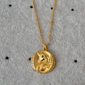 Gros plan du pendentif licorne plaqué or avec œil en pierre verte et cristaux fins