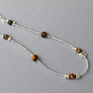 Detailed close-up of tiger eye beads and silver cut beads on a double-layer necklace
