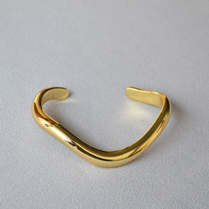 Minimalist gold plated wave bracelet featuring a high-polished mirror finish and dynamic curves