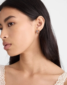 Gros plan de boucles d'oreilles en laiton doré avec pierres bleues et grises sur mannequin