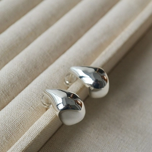 Macro shot of silver teardrop stud earrings featuring polished finish and soft reflections