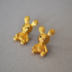 Detail of gold rabbit stud earrings with textured finish and cute black dot eyes
