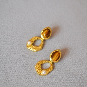 Détail de boucles d'oreilles œil de tigre vintage avec laiton martelé et perles