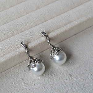 Detailed view of vintage silver floral earrings with glossy white pearls and zircons
