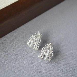 Detailed view of silver lace hollow earrings with three vertical white pearls inlay
