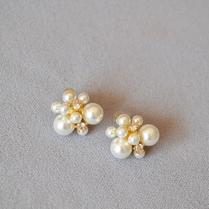 Détail d'une boucle d'oreille en grappe avec perles blanches et zircons cubiques
