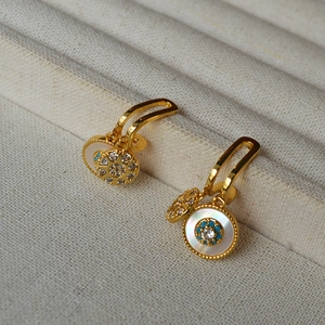 Detailed close-up of white mother of pearl earrings with blue beads and zircon centers