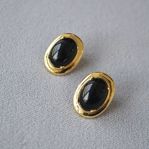 Détail macro de boucles d'oreilles onyx noir ovale avec monture en laiton plaqué or