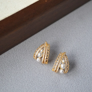 Macro view of gold lace earrings with white pearls and sparkling zircon in French style