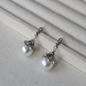 Detailed view of silver flower earrings with white pearls and sparkling pavé crystals
