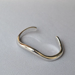 Close-up of a silver irregular wavy cuff bracelet with a high-polished mirror finish