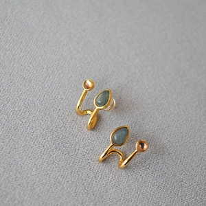 Détail macro de boucles d'oreilles spirales dorées avec pierres bleues en goutte d'eau