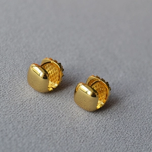 Macro shot of gold-plated geometric hoop earrings with polished finish and hollow mesh texture