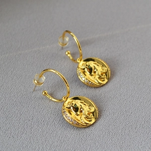 Détail de boucles d'oreilles licorne dorées avec pierres vertes et accents de zircon blanc