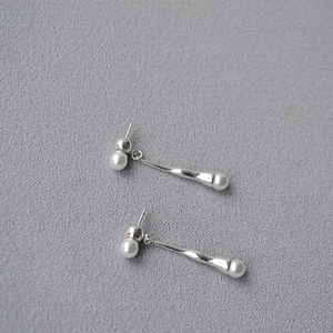 Detail of silver long drop earrings with white pearls and twisted metal texture