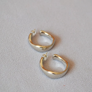 Macro detail of silver irregular C-shaped earrings with molten liquid metal texture