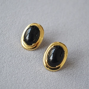 Vue macro de boucles d'oreilles ovales en onyx noir avec monture en laiton doré poli