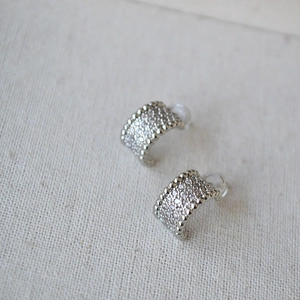 Elegant silver C-shaped clip-on earrings with pavé cubic zirconia on fabric background