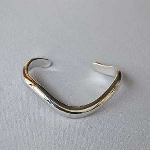 Macro shot of silver wave-shaped brass cuff bracelet with high-polished mirror finish