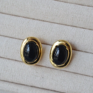 Boucles d'oreilles vintage dorées à l'onyx noir sur un plateau en velours beige