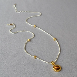 Detailed view of vintage double-layer necklace with tiger eye stone on grey fabric