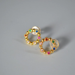 Détail de boucles d'oreilles couronne de gemmes colorées avec finition dorée et fermoir