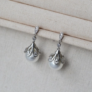 Macro shot of silver pearl drop earrings with sparkling flower petals and zircon stones