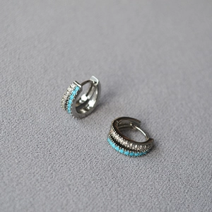Macro detail of silver plated brass hoop earrings with pavé zircons and turquoise stones