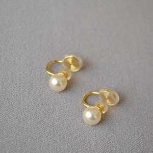 Détail de boucles d'oreilles clips perles avec attache dorée et coussinet en silicone