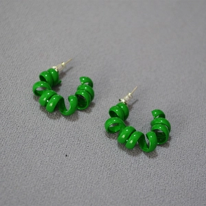 Macro shot of vibrant green spiral stud earrings with high-gloss enamel finish