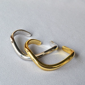 Close-up of overlapping gold and silver irregular wavy open bangles on fabric