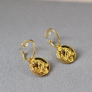 Détail de boucles d'oreilles cheval vintage en laiton doré avec gemmes et zircons