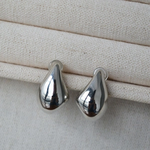 Minimalist silver organic teardrop earrings with high-polish finish on fabric jewelry box