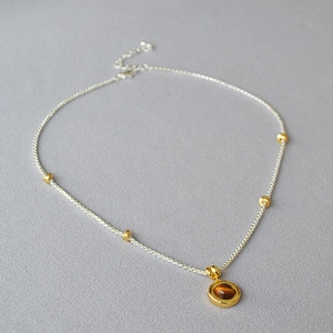 Detail of tiger eye stone pendant and silver beaded chain with adjustable clasp