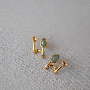 Gros plan de boucles d'oreilles spirales dorées avec pierres bleues et roses rondes