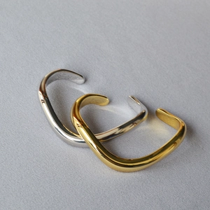 Detail of stacked gold and silver wave bracelets with a premium mirror finish