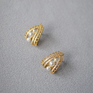 Detail of vintage gold earrings featuring lace hollow design with white pearls and crystals