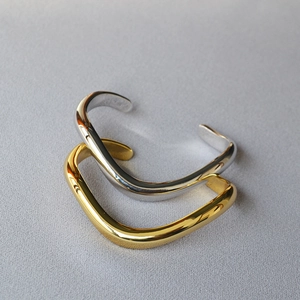 Detail view of wavy irregular brass bangles in polished gold and silver finishes
