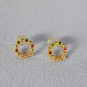 Boucles d'oreilles couronnes dorées délicates avec zircons colorés sur fond gris