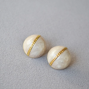 Détail de boucles d'oreilles vintage en émail perlé avec texture de chaîne dorée