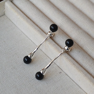 Detail of elegant silver drop earrings with black agate beads on a soft fabric display