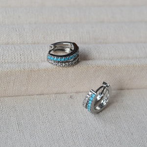 Detail of silver huggie earrings featuring turquoise stones and double row pavé zircons
