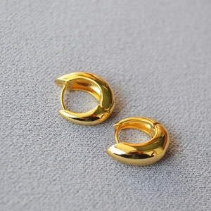 Polished 18k gold plated asymmetrical C-shape hoop earrings on grey textured fabric