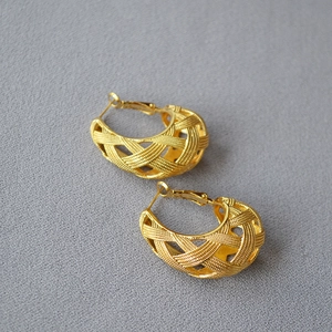 Macro detail of gold-plated hollow mesh earrings featuring vintage woven texture craftsmanship