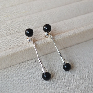 Macro shot of silver teardrop earrings featuring smooth black agate beads and minimalist style